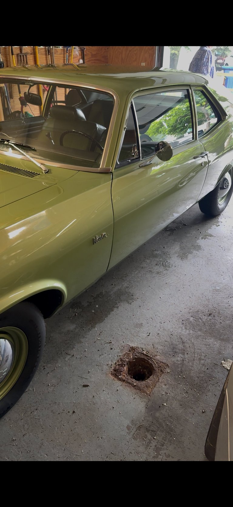 Vintage lime green car parked next to a pothole on a concrete street