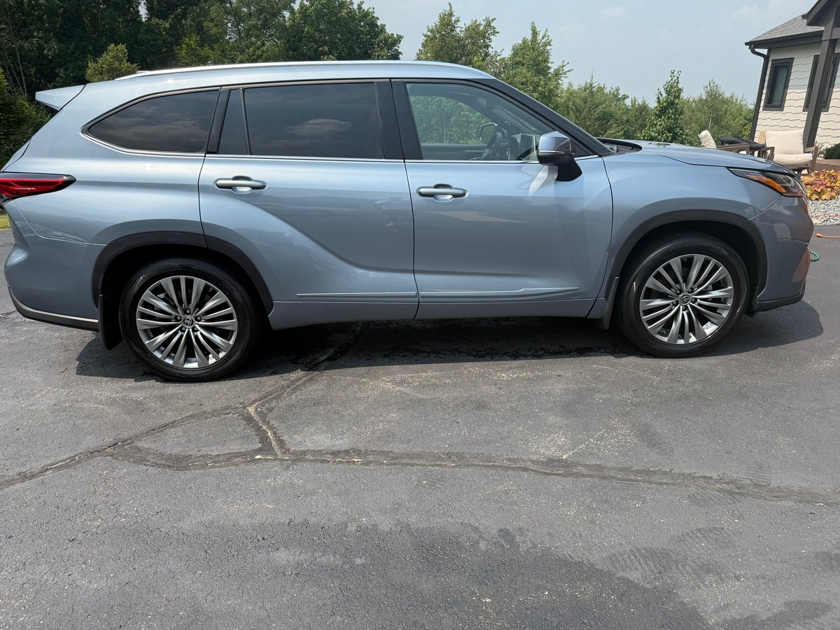 Silver Lexus SUV parked on driveway with trees and house in background